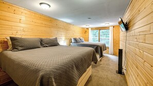 Ett rum med två sängar, träpanel på väggarna, en taklampa och en tv som är monterad på väggen.