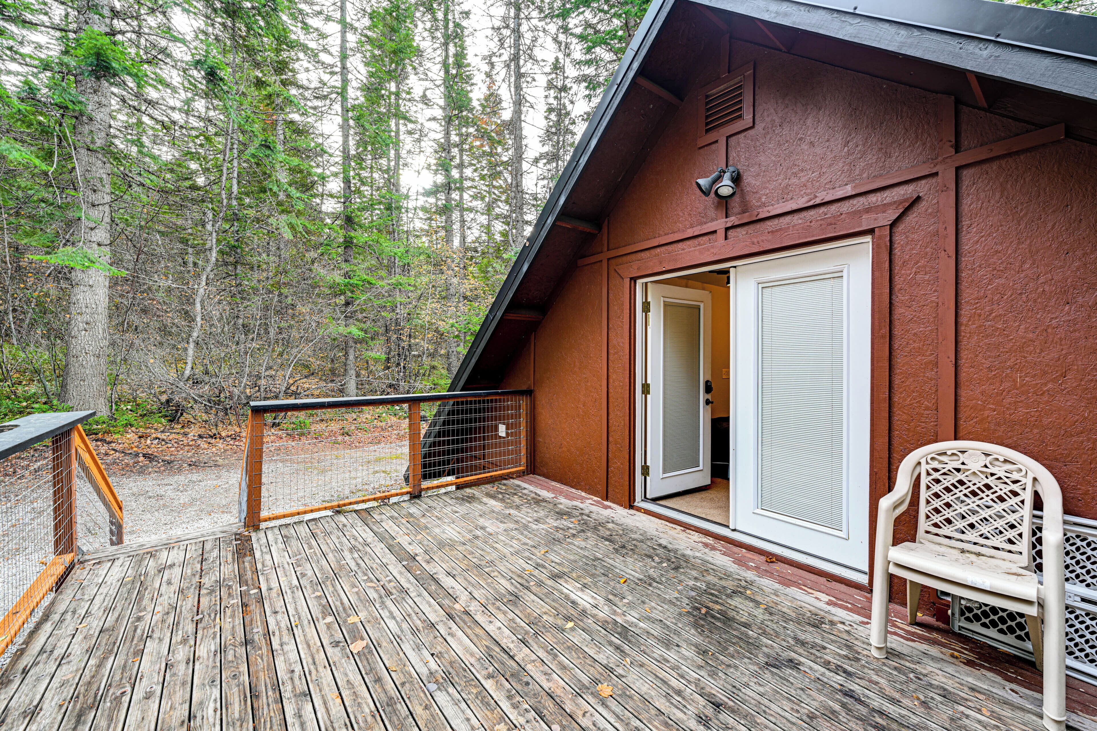 Une terrasse en bois avec une rambarde en métal, une porte blanche et un banc.