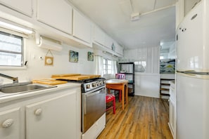 A compact kitchen with a stove, sink, and wooden countertop.