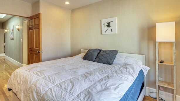 A bedroom with a large bed, a wooden wardrobe, a painting on the wall, and a bedside table with a lamp. - Walkable Home w/ Office in Downtown Albuquerque! (Albuquerque)