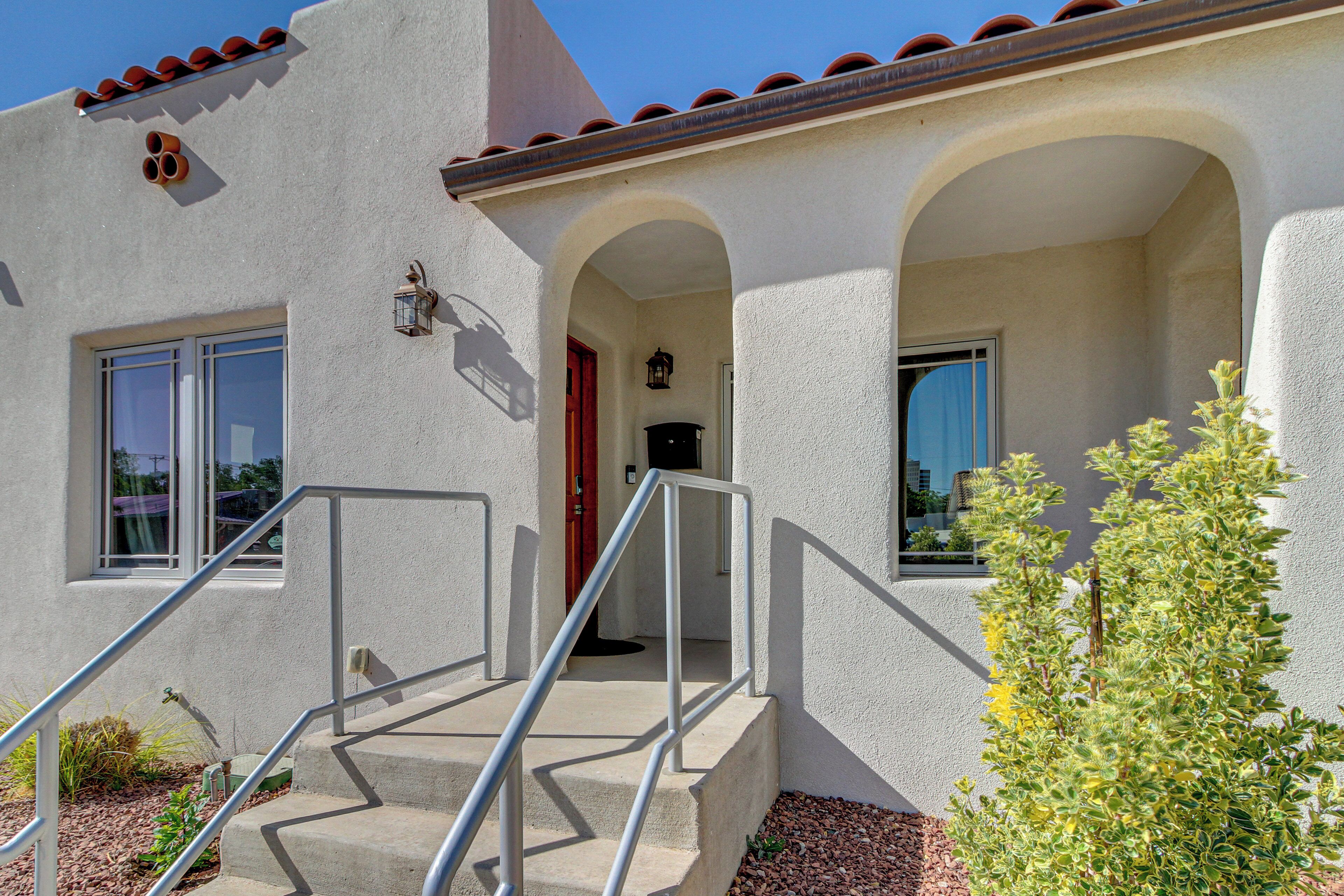 A building with a stucco exterior, a set of concrete stairs with metal railings, and a small plant in the foreground.