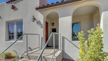 A building with a stucco exterior, a set of concrete stairs with metal railings, and a small plant in the foreground.