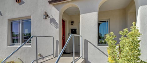 A building with a stucco exterior, a set of concrete stairs with metal railings, and a small plant in the foreground.
