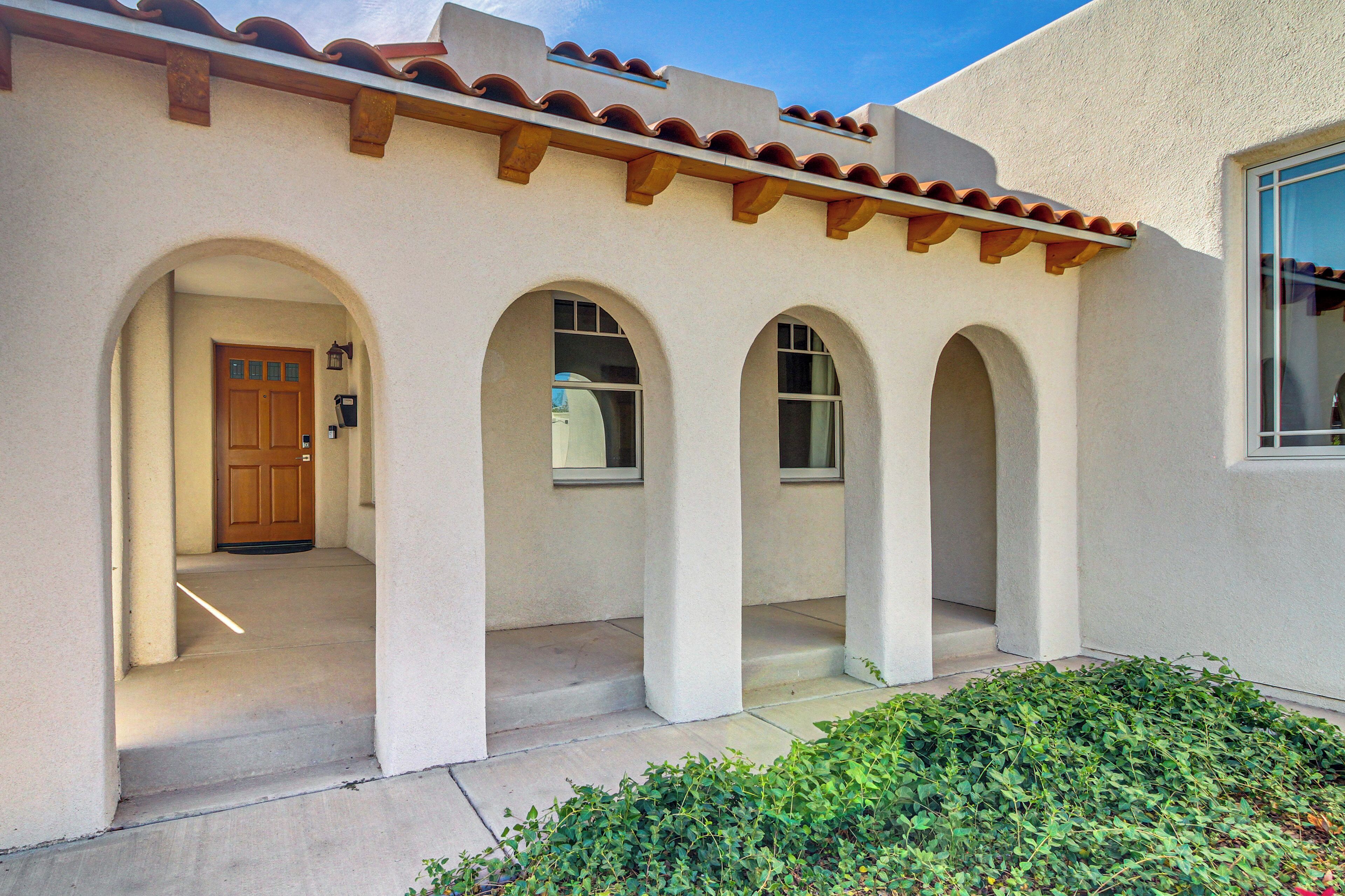 A building with a covered entrance, arched windows, and a door.