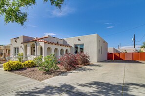 A building with a modern architectural style, featuring a flat roof, arched windows, and a concrete entrance area.