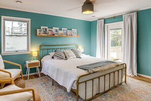 A bedroom with a bed, bedside tables, a chair, a window, and a view of the outside.