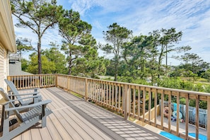 Eine Holzterrasse mit Geländer, einem Pool und Blick auf Bäume.