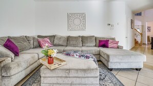 A living room with a sectional sofa, a coffee table with a tray, and a decorative wall piece. - Arlington Home: Pool Oasis Near At&t Stadium (Grand Prairie)