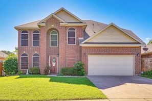A two-story house with a garage, a front lawn, and a brick facade. - Arlington Home: Pool Oasis Near At&t Stadium (Grand Prairie)
