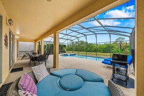 Un'area esterna coperta con piscina, posti a sedere e barbecue.