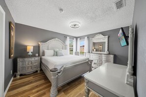 Ein Schlafzimmer mit einem großen Bett, einem Nachttisch, einer Kommode und einem Spiegel.