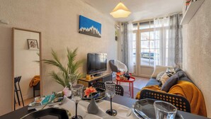 Una sala de estar amoblada con televisor, comedor y sofá.