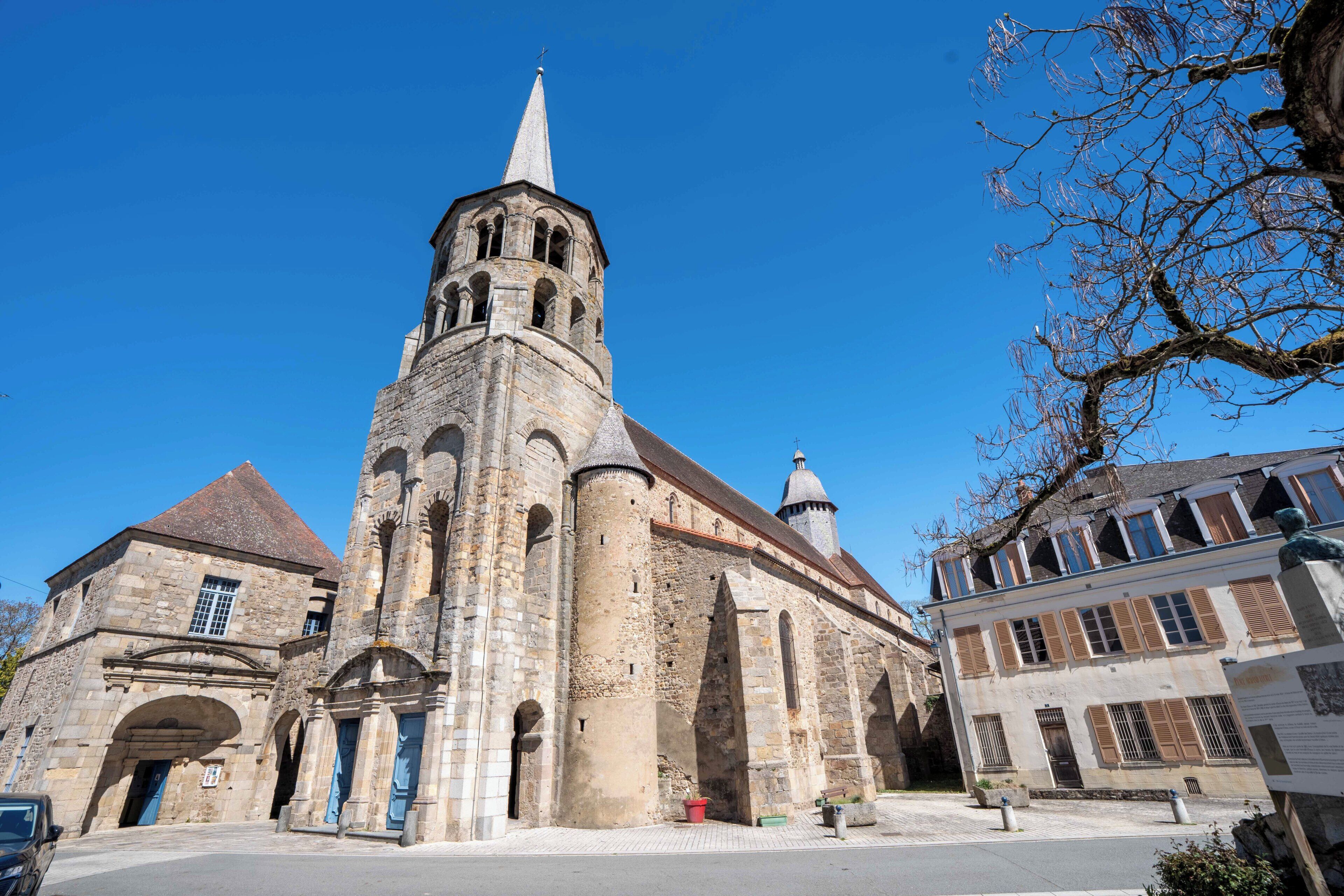 A historic church with a prominent bell tower, a courtyard, and adjacent buildings.