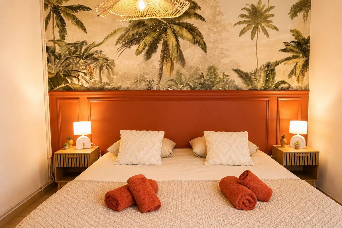 A hotel room with a large bed, two nightstands, a wall mural, and a ceiling fan.