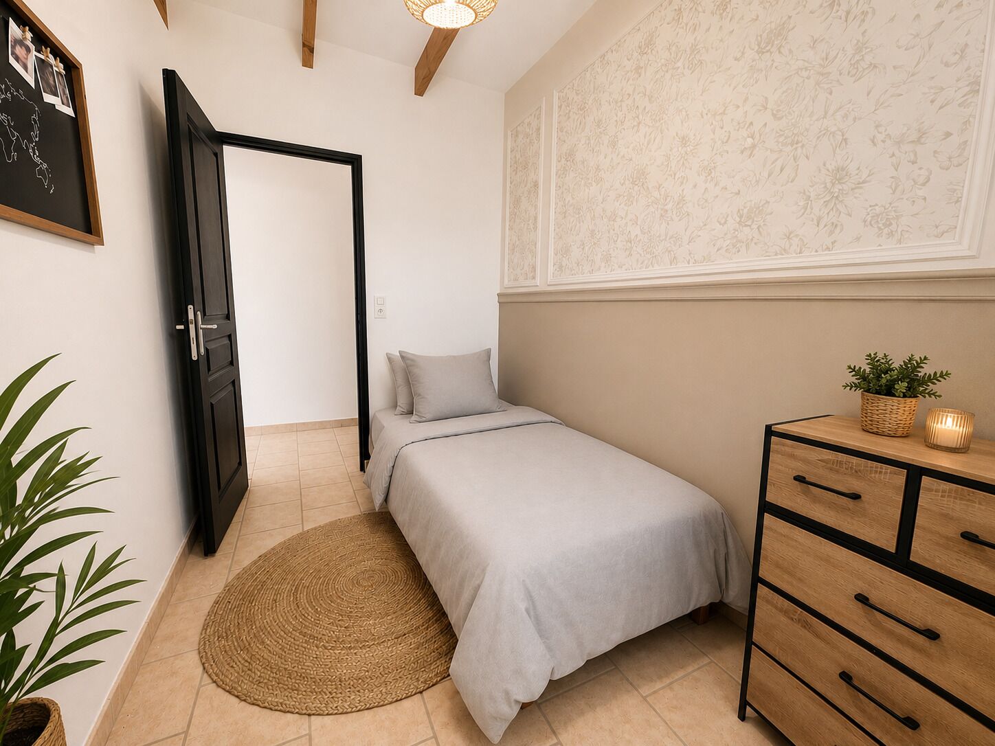 Un dormitorio con cama, cómoda, alfombra redonda tejida, planta en maceta y pared con estampado floral.