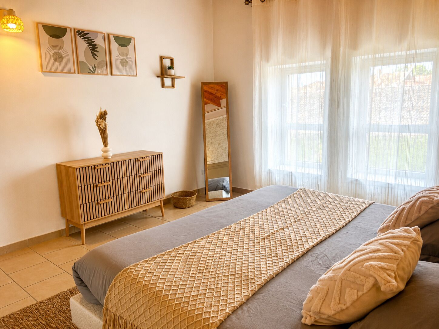 A bedroom with a bed, a wooden dresser, a mirror, and artwork on the wall.