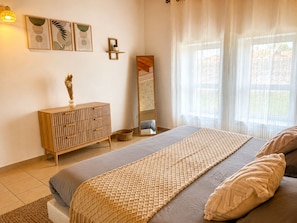 A bedroom with a bed, a wooden dresser, a mirror, and artwork on the wall. - Apart'Moment - Résidence La Brasserie (Aire-sur-la-Lys)