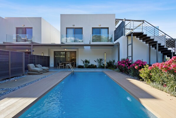 A modern house with a swimming pool, a staircase, and outdoor seating.
