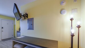 A small kitchenette with a microwave, a sink, and a countertop. There is a flat-screen TV mounted on the wall, and a light fixture with two bulbs. - Walk to Boardwalk & Beach! Ocean City Studio (Ocean City)