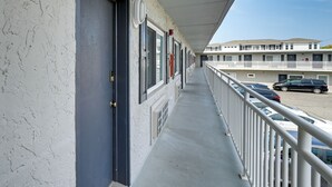 A long corridor with a balcony on one side, leading to a parking area with several cars. - Walk to Boardwalk & Beach! Ocean City Studio (Ocean City)