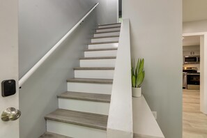 A staircase with a handrail, a potted plant, and a modern kitchen in the background. - Modern Home, Minutes to Mystic, Casinos and Ocean (Groton)