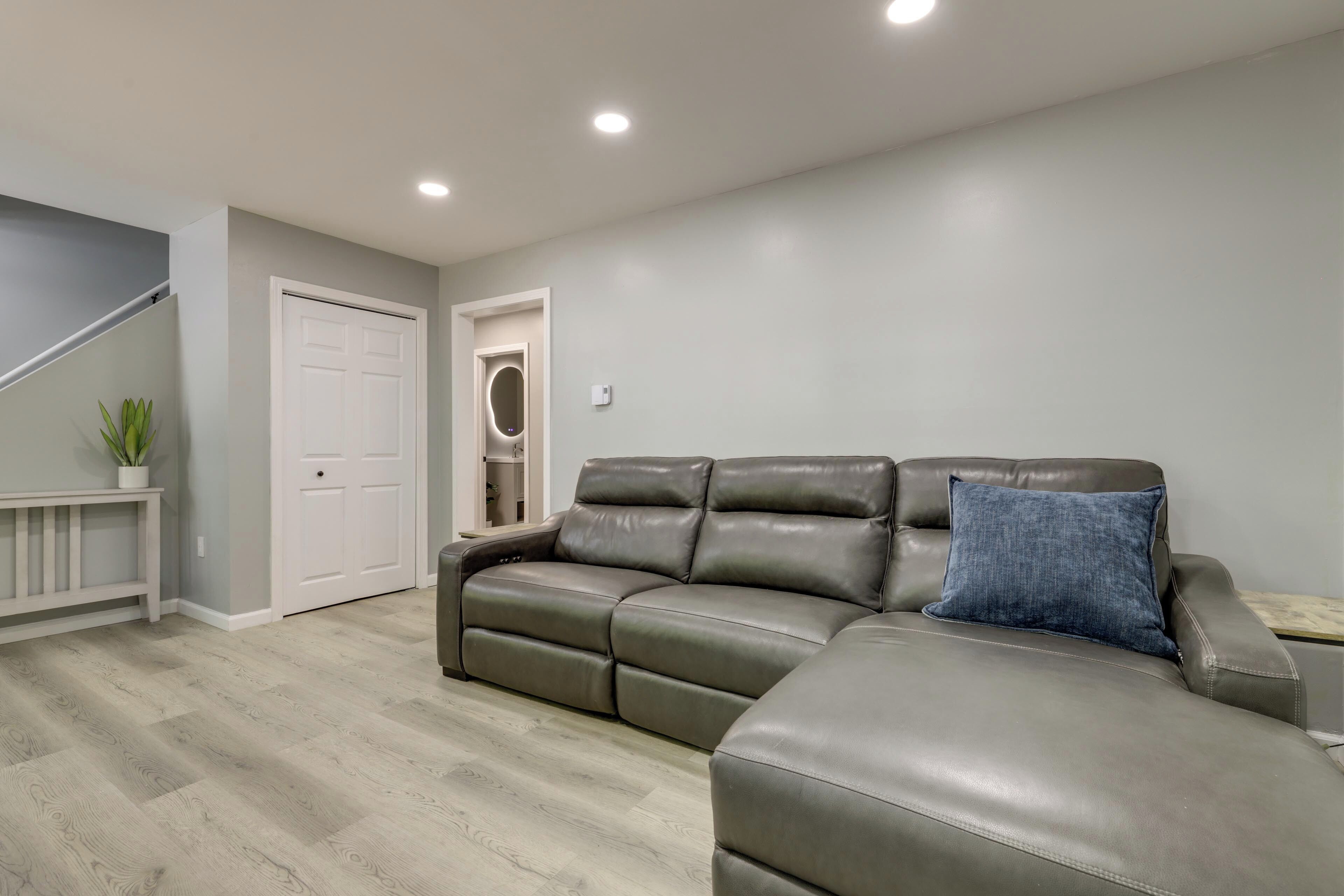 Una sala de estar con un sofá modular, una puerta blanca y una escalera.