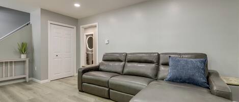 Una sala de estar con un sofá modular, una puerta blanca y una escalera.