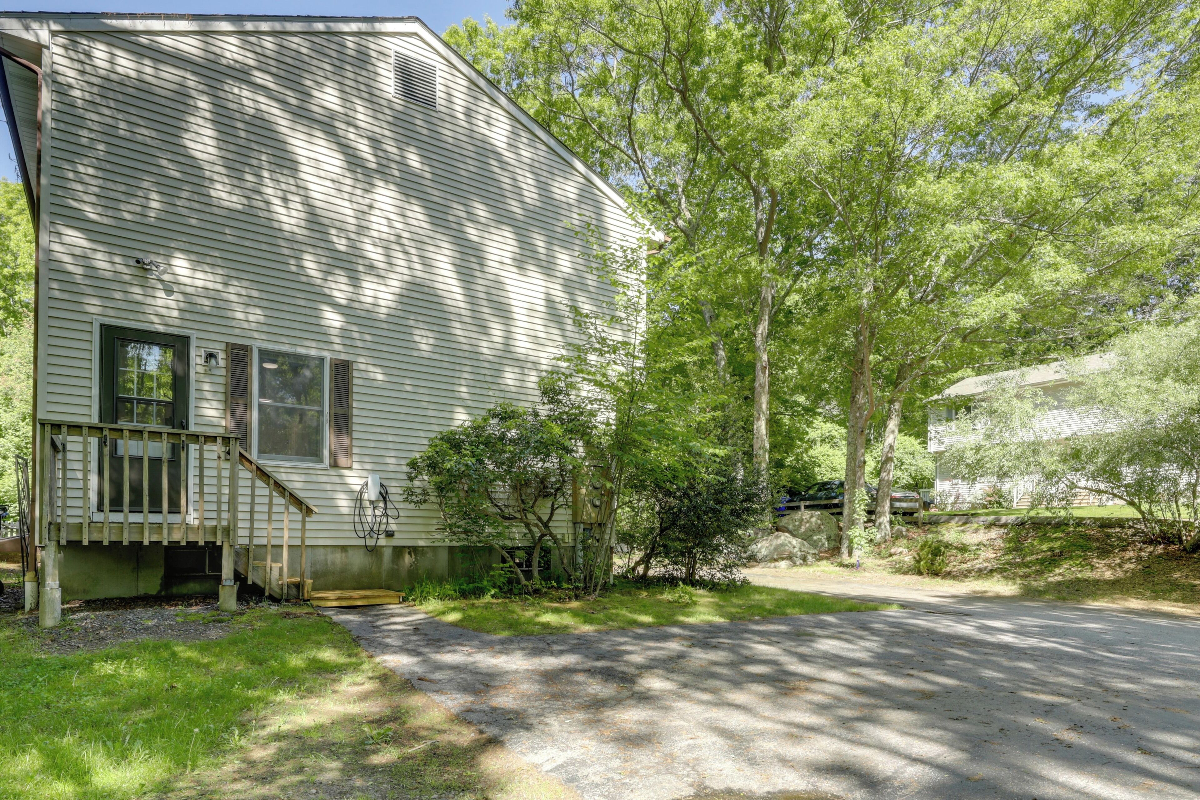 A two-story house with a front porch, a driveway, and surrounding trees.