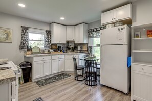 A kitchen with white cabinets, a refrigerator, a dining table with chairs, and a window with curtains. - 2 Mi to Beach & Boardwalk! New London Haven (New London)