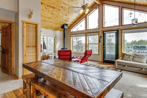 Un tavolo da pranzo in legno con panche, una sedia rossa, un divano e un camino.