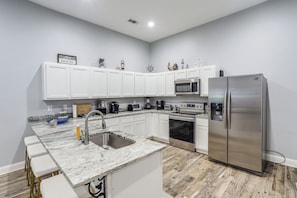A modern kitchen with white cabinets, a stainless steel refrigerator, a microwave, and a sink. - Woodsy + Peaceful! Family-friendly Getaway in Iuka (Iuka)