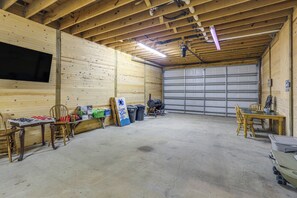 Ett rymligt garage med ett betonggolv, träväggar, en stor garagedörr och ett bord med stolar.