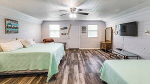 A bedroom with two beds, a ceiling fan, a TV, and a door with a sign.
