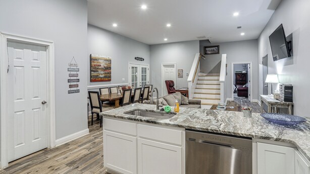 A modern kitchen with a central island, built-in dishwasher, and a dining area with a wooden table and chairs.