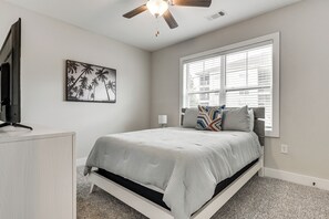 A bedroom with a bed, a ceiling fan, a window with blinds, a wall-mounted TV, and a framed picture. - Golf + Poolside Days! Condo 9 Mi to Sunset Beach (Calabash)