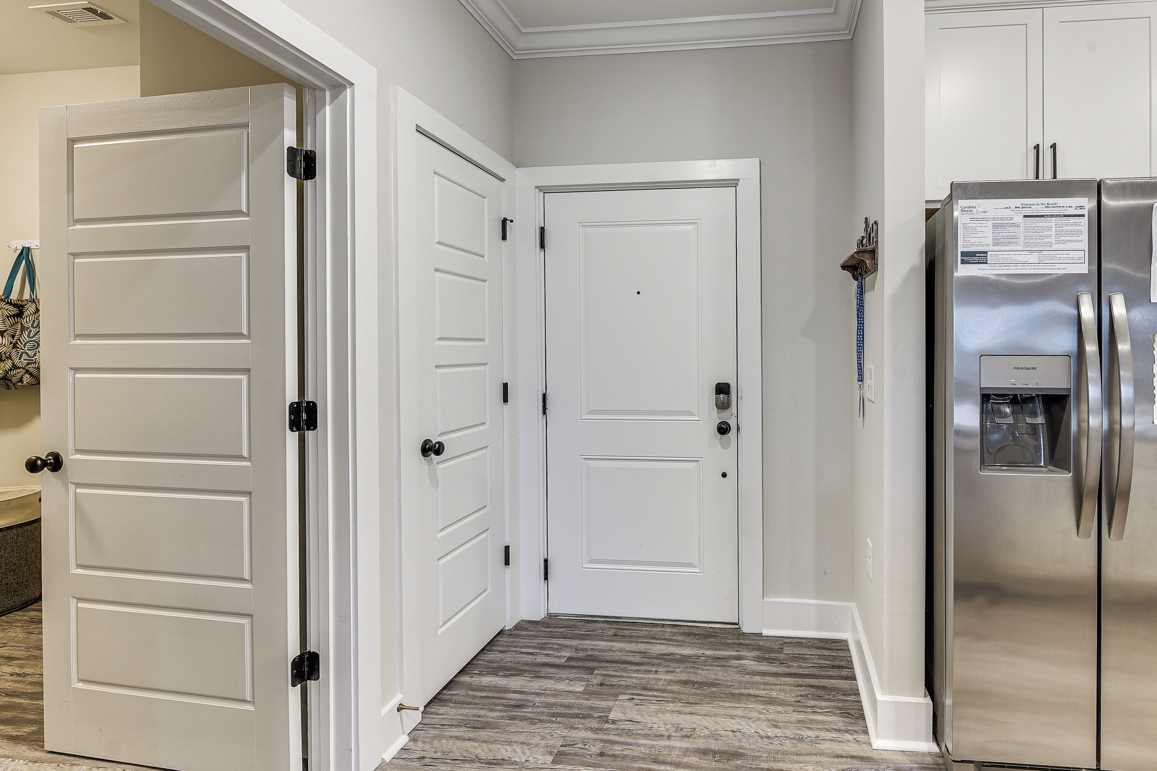 A hallway with white double doors, a stainless steel refrigerator, and a patterned floor.