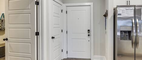 A hallway with white double doors, a stainless steel refrigerator, and a patterned floor.