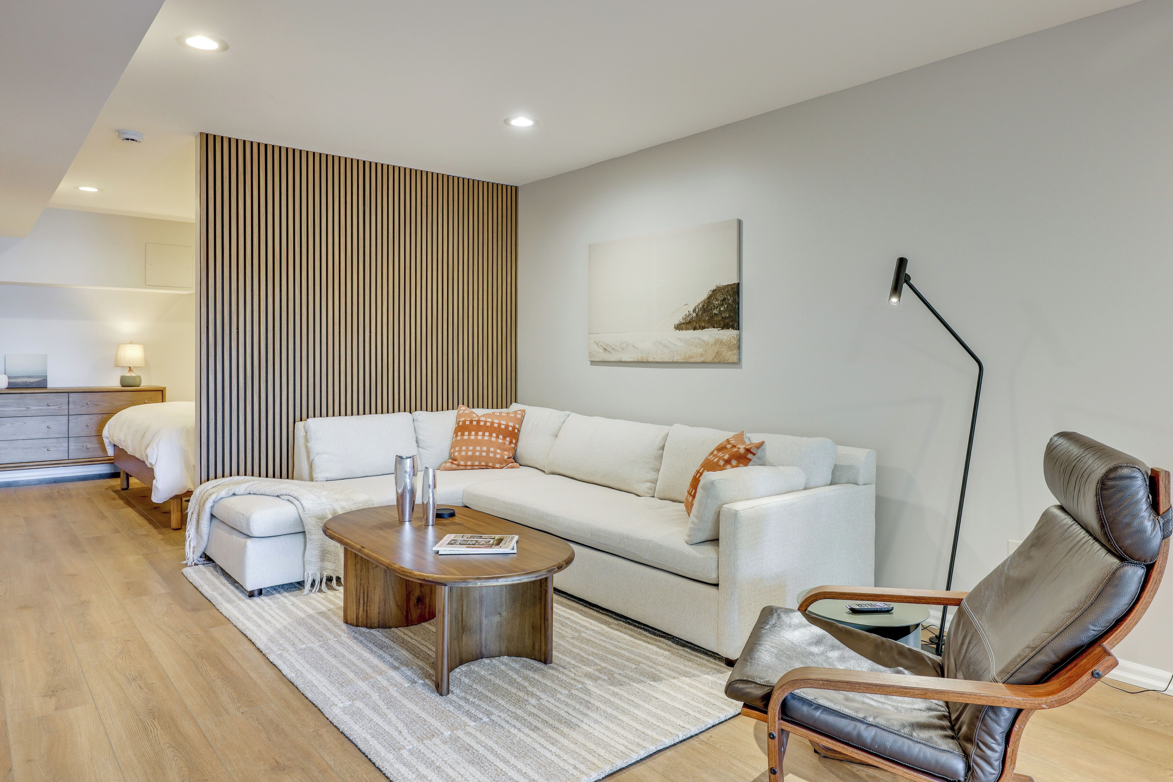 A modern living room with a sofa, a coffee table, a leather armchair, and a floor lamp.