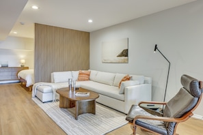 Uma sala de estar moderna com um sofá, uma mesa de centro, uma poltrona de couro e um abajur.