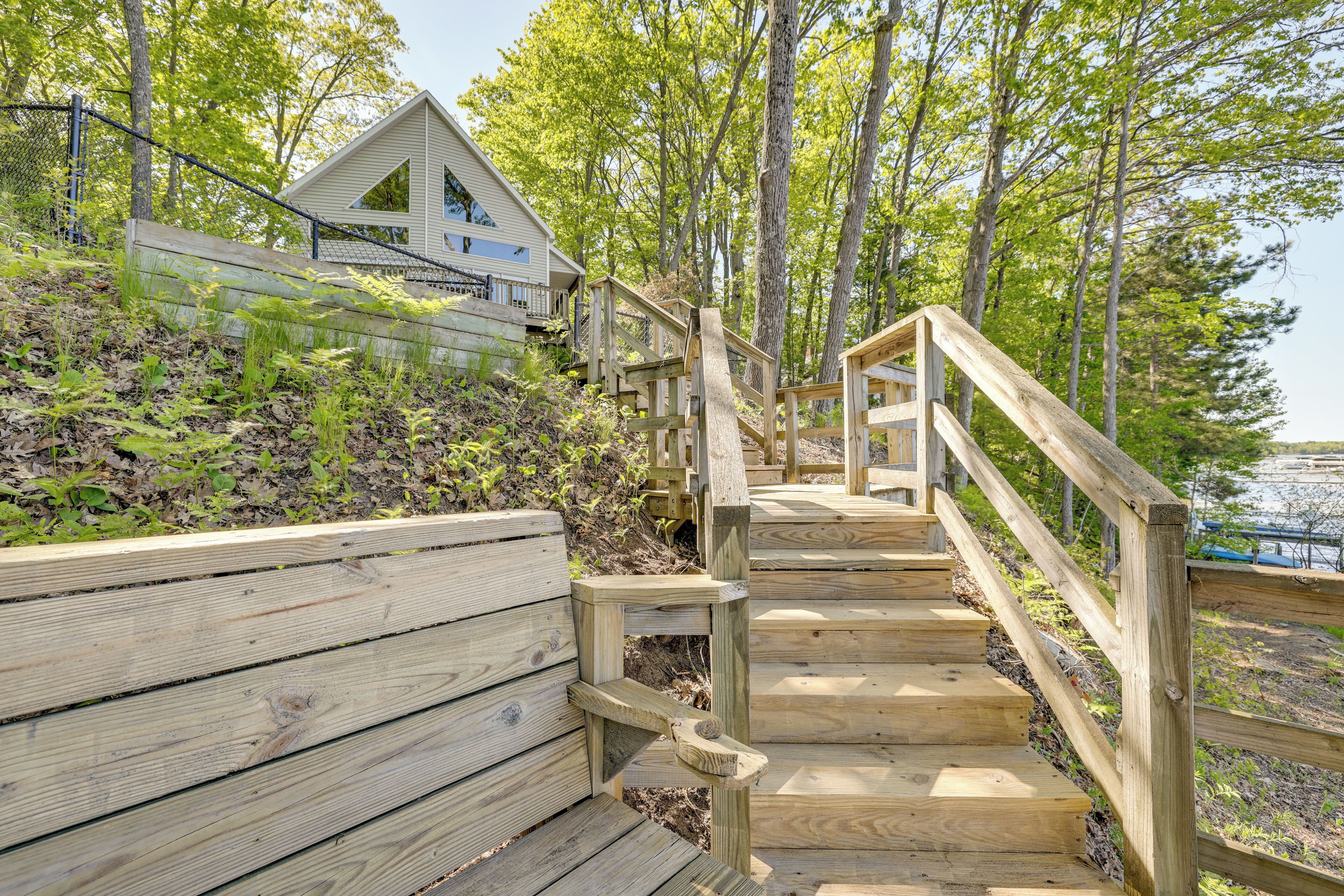 A wooden staircase leading to a house with a sloped roof, surrounded by trees.