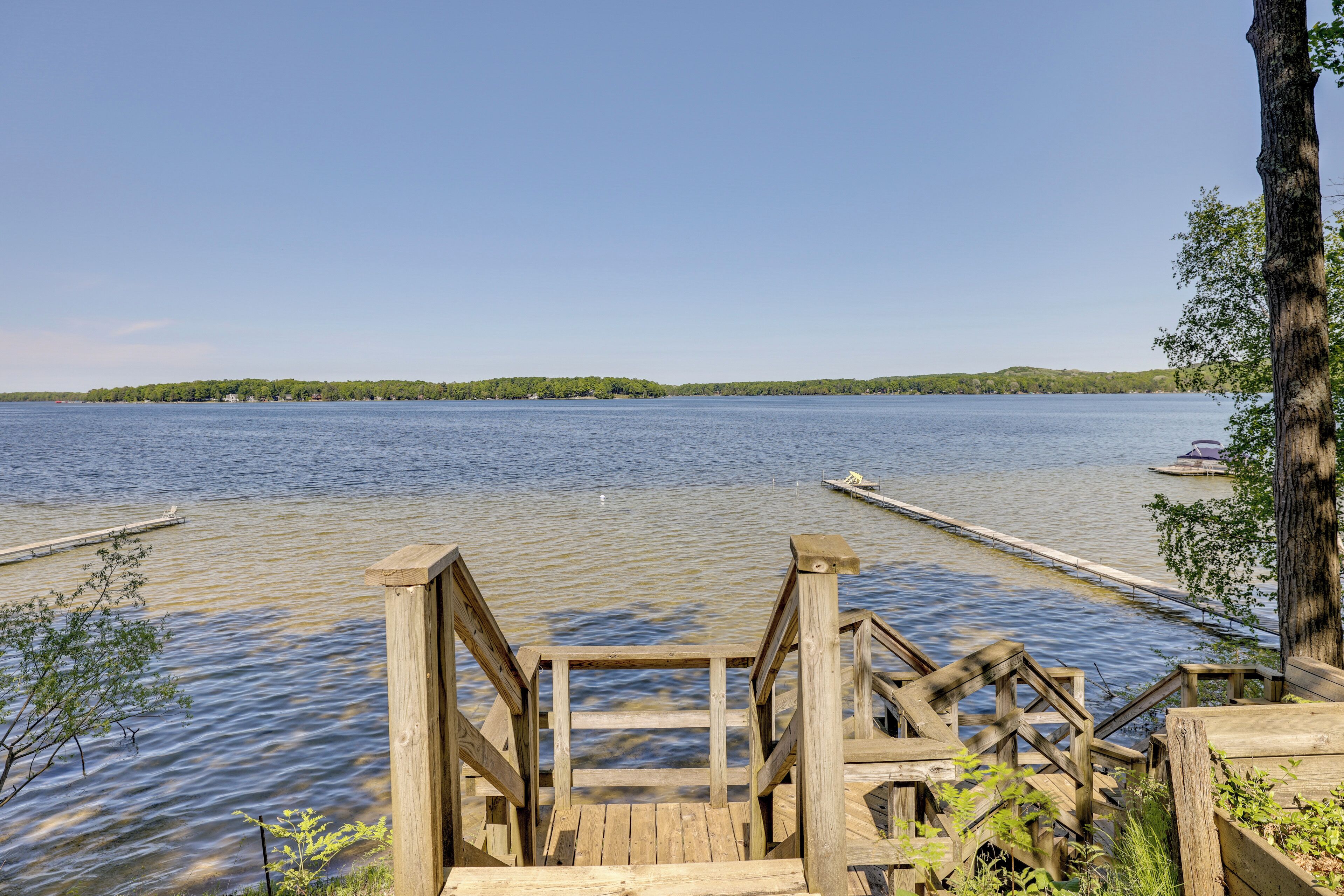 Un muelle de madera que se extiende hacia un lago tranquilo con cielo despejado.