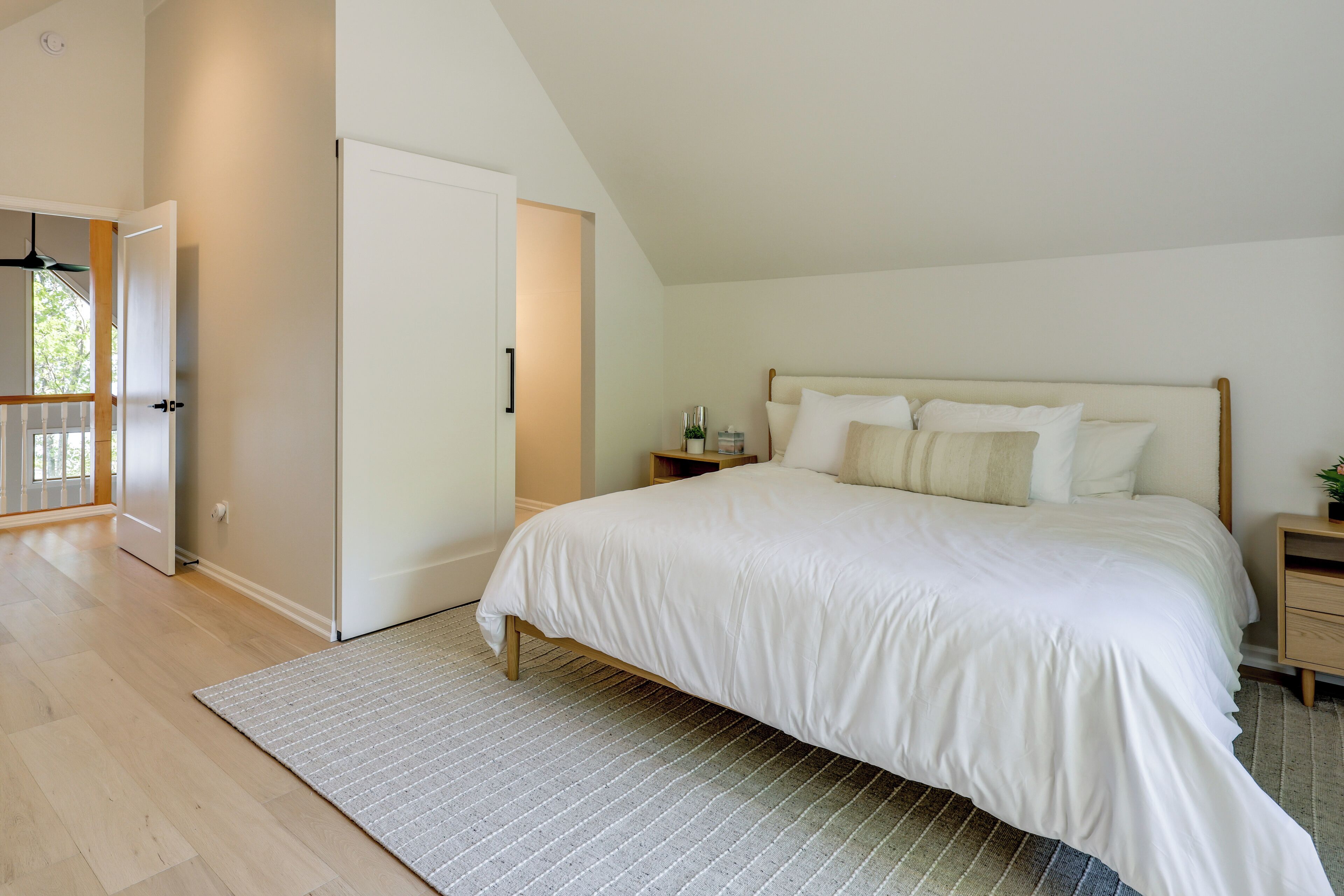 Une chambre à coucher avec un lit, une table de chevet, une porte et une fenêtre.