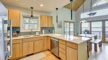 A modern kitchen with wooden cabinets, a dishwasher, and a large island.