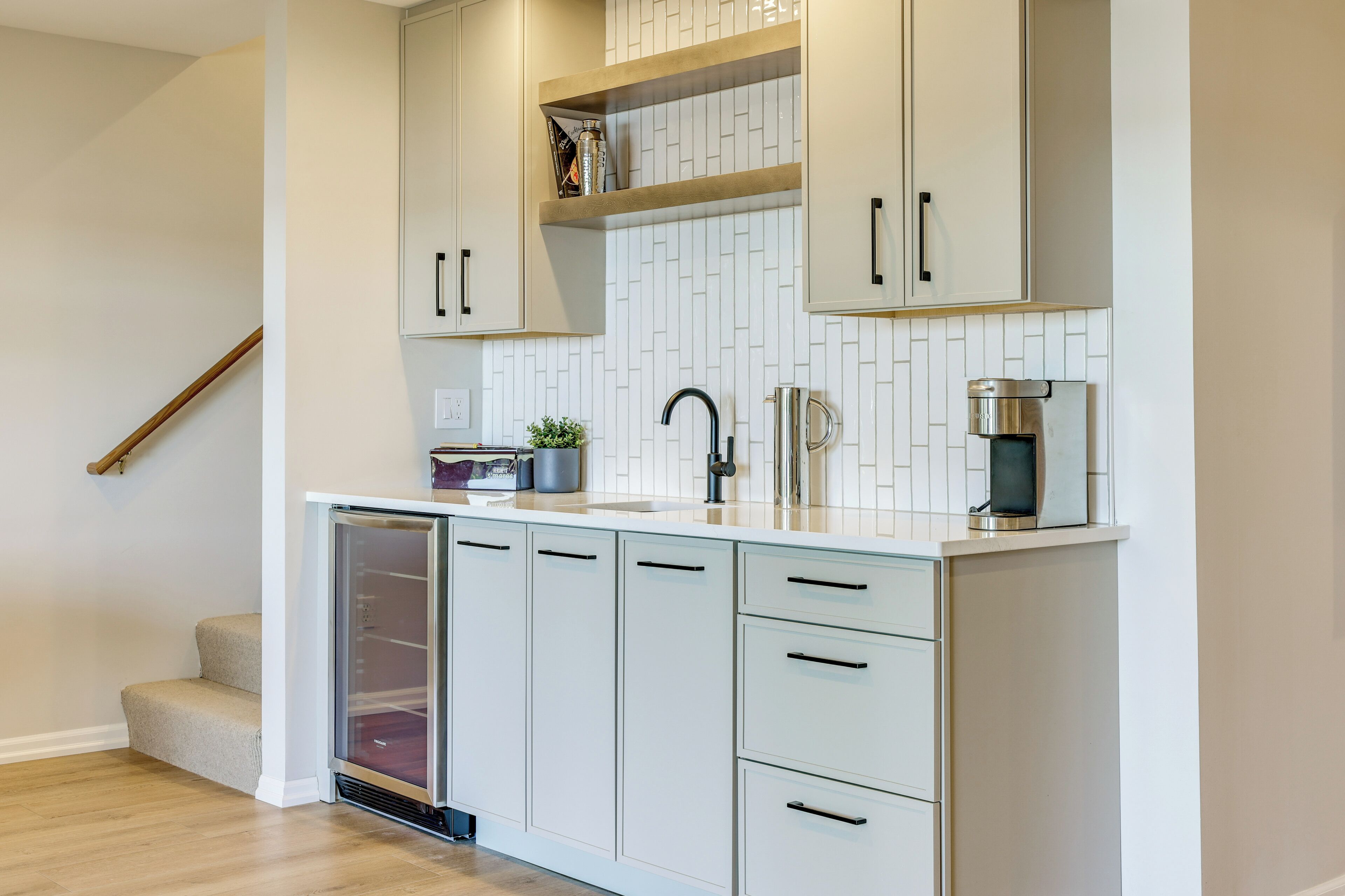 A kitchen with white cabinets, a stainless steel sink, and a coffee machine.