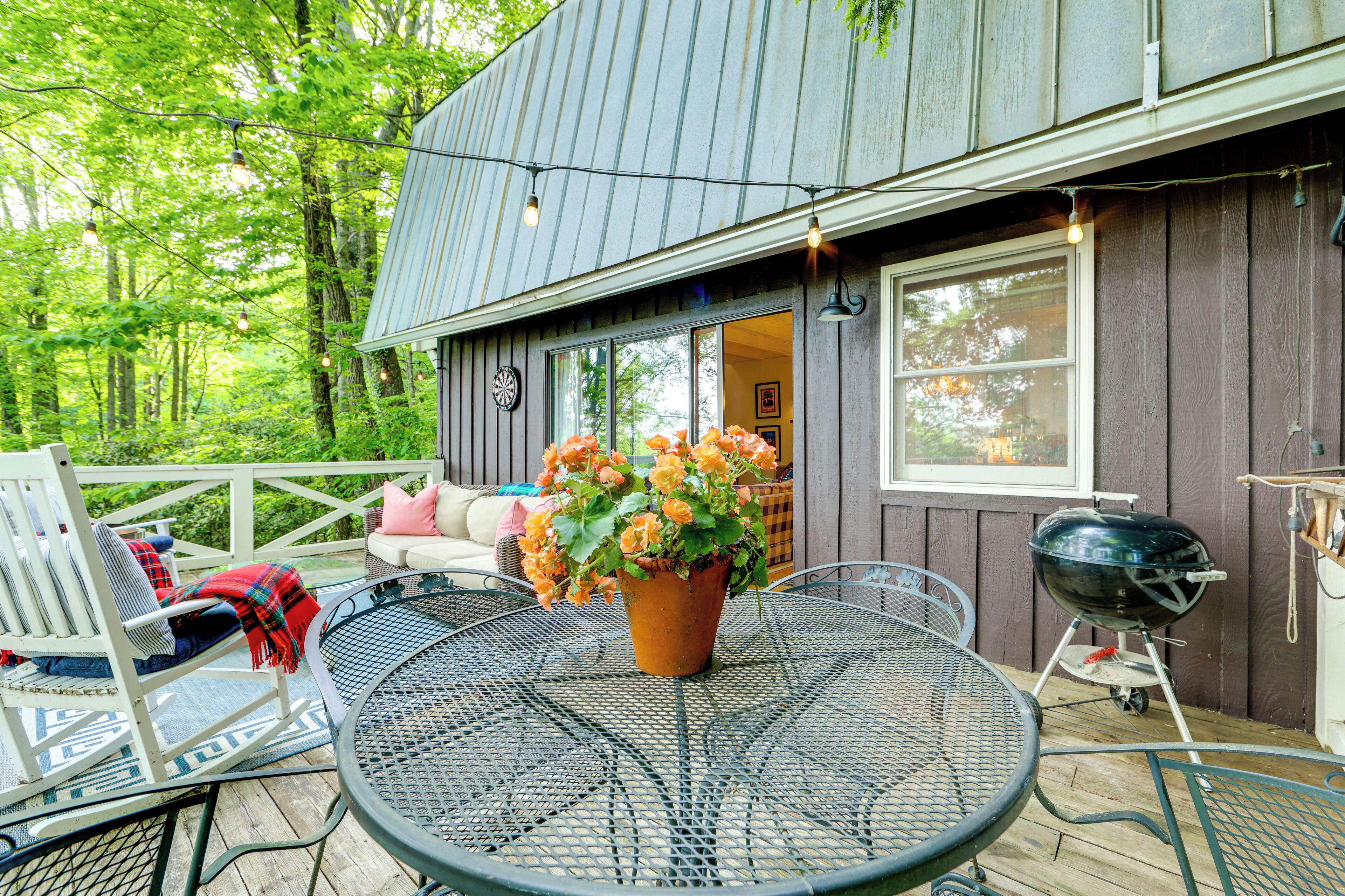 A wooden deck with outdoor furniture, a barbecue grill, and a potted plant.