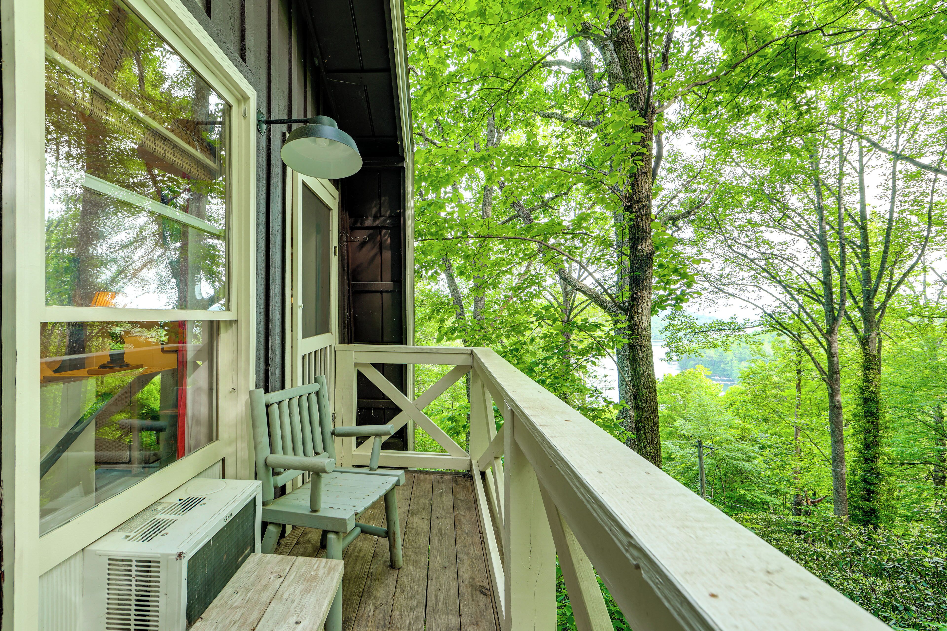 A wooden deck with a table and chair, overlooking a forested area.