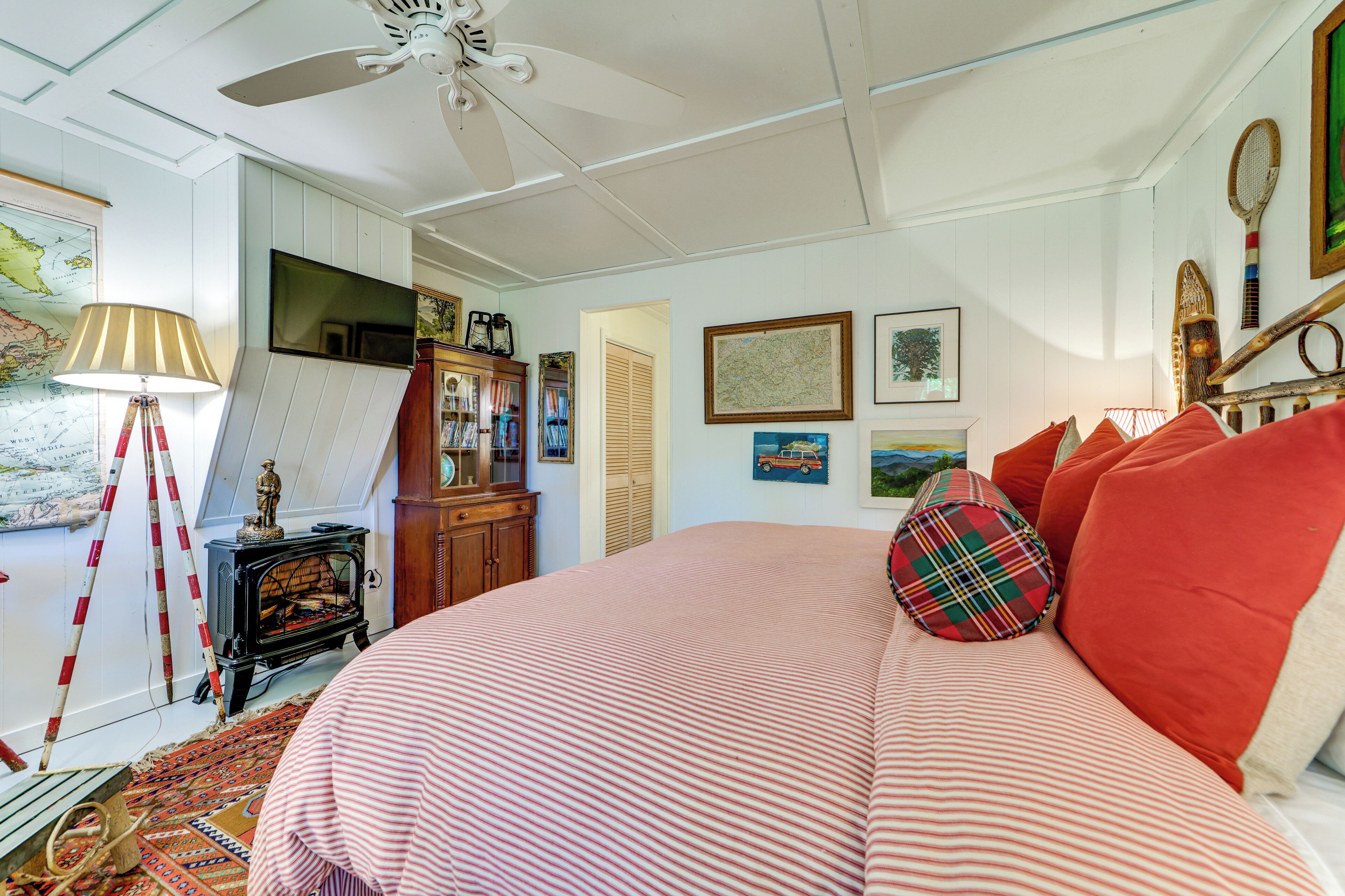 A bedroom with a bed, a ceiling fan, a map on the wall, and a television.
