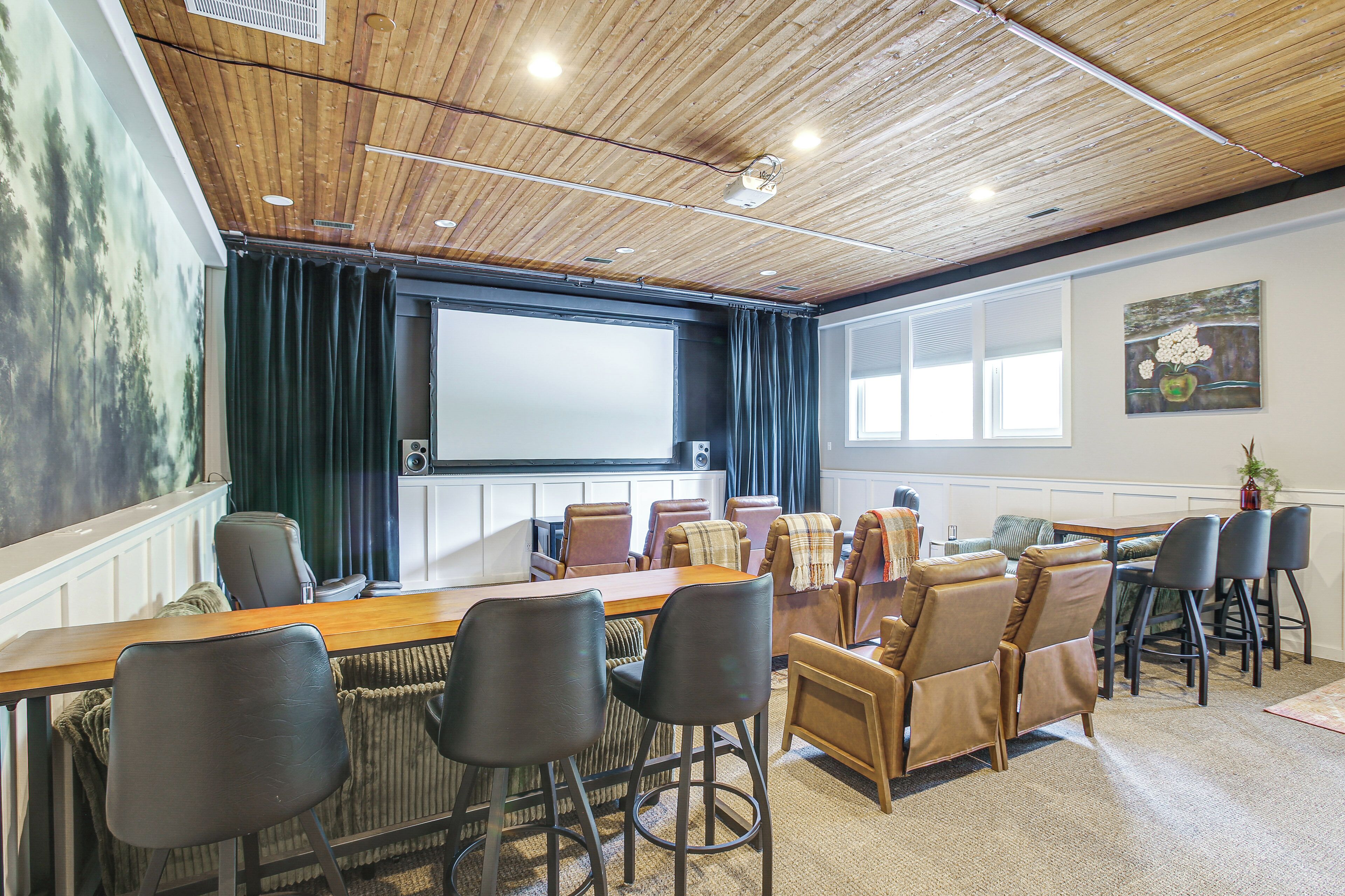 A conference room with a wooden ceiling, a large screen, and a mix of leather and fabric chairs.