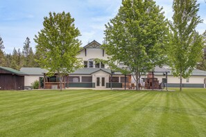 A two-story building with a large lawn in front, a garage, and a covered outdoor seating area.