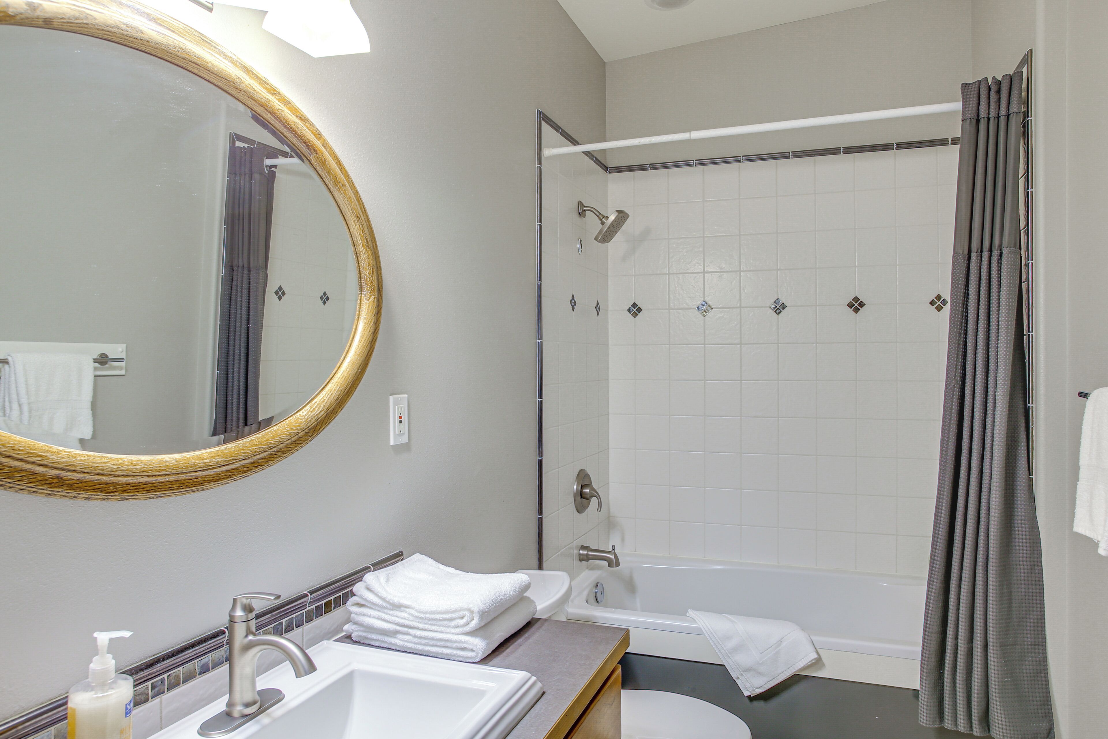 A bathroom with a sink, mirror, shower, and bathtub.